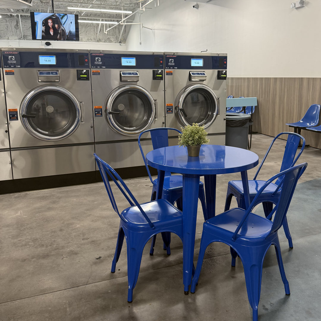 Modern LaundryJack laundromat interior with large-capacity washers, blue seating, and a clean waiting area.